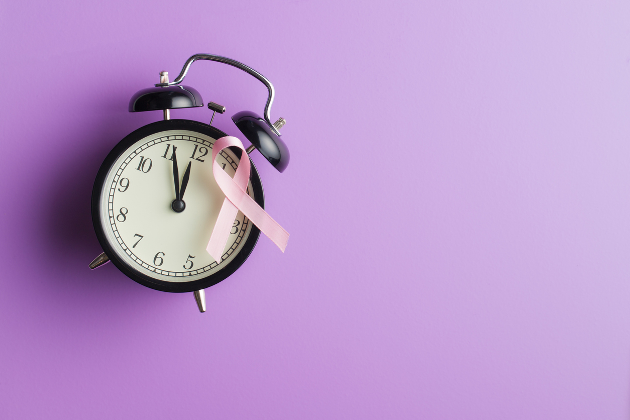 Pink breast cancer ribbon on alarm clock